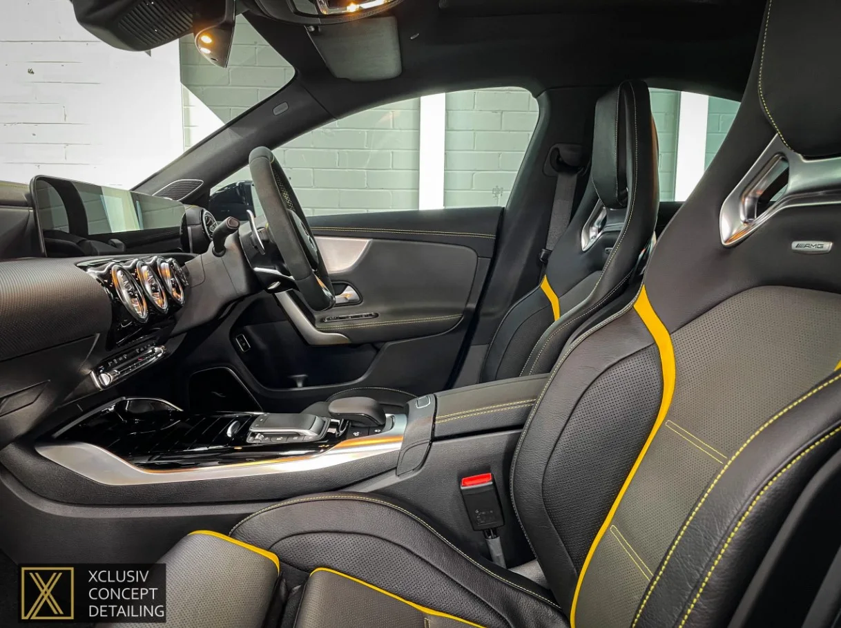 Interior of a luxury car featuring black leather seats with yellow accents, a sleek dashboard, and modern controls. The branding XCLUSIV CONCEPT DETAILING appears in the bottom left corner.